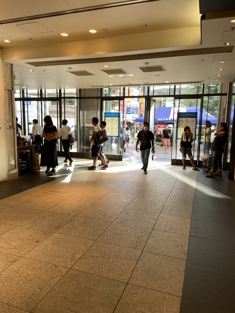 駅ビル内通路の画像。向う側には屋外に通じるガラス張りの扉が見える。日差しが差し込んでいる。