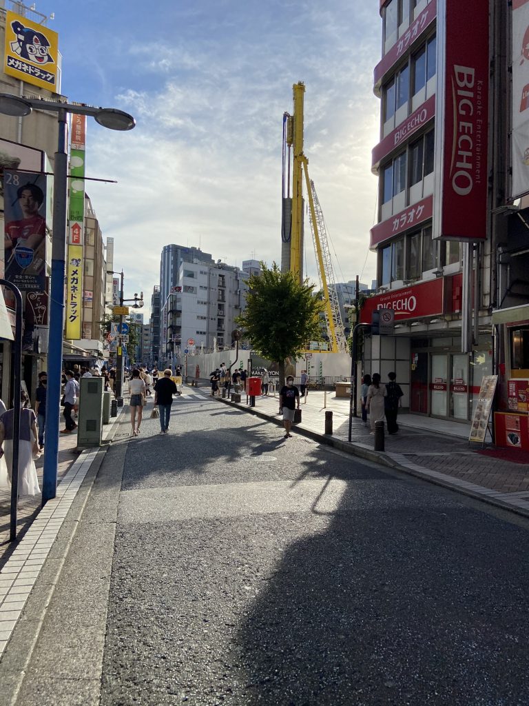 道路画像。中央縦に道路。左側にメガネドラッグ、右側にビッグエコーの看板。