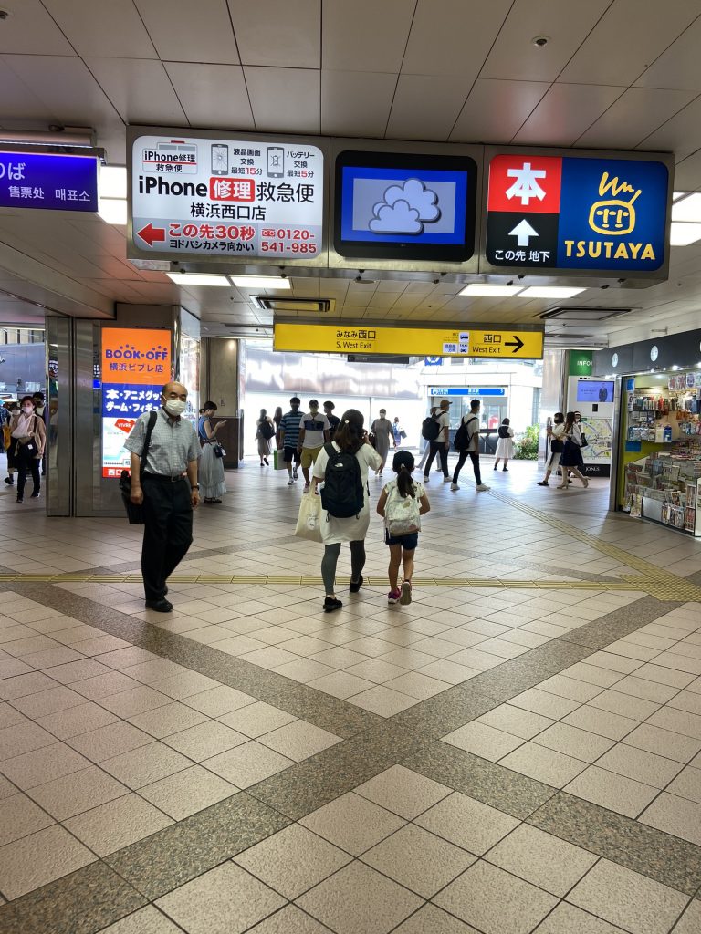 横浜駅みなみ西口改札を出た広場の画像。数人が行き来。通路上にはtsutaya等の案内看板あり。